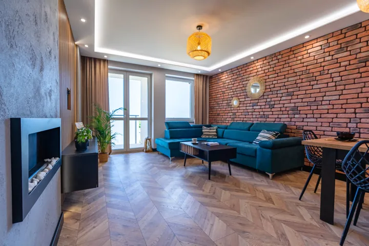 Salon z granatowym narożnikiem i ceglaną ścianą