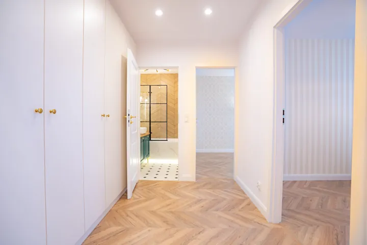Przedpokój z parkietem w jodełkę i białą zabudową